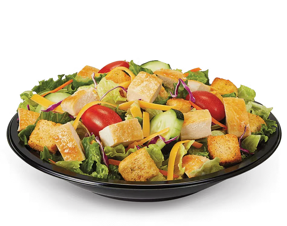 Culver’s Garden Fresco Salad with mixed greens, grape tomatoes, cucumbers, shredded cheese, and croutons in a clear bowl